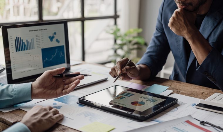A group of smart young Asian businessmen come together to analyze financial data graphs in the workplace. Young entrepreneurial team. Present the project until the management is satisfied.